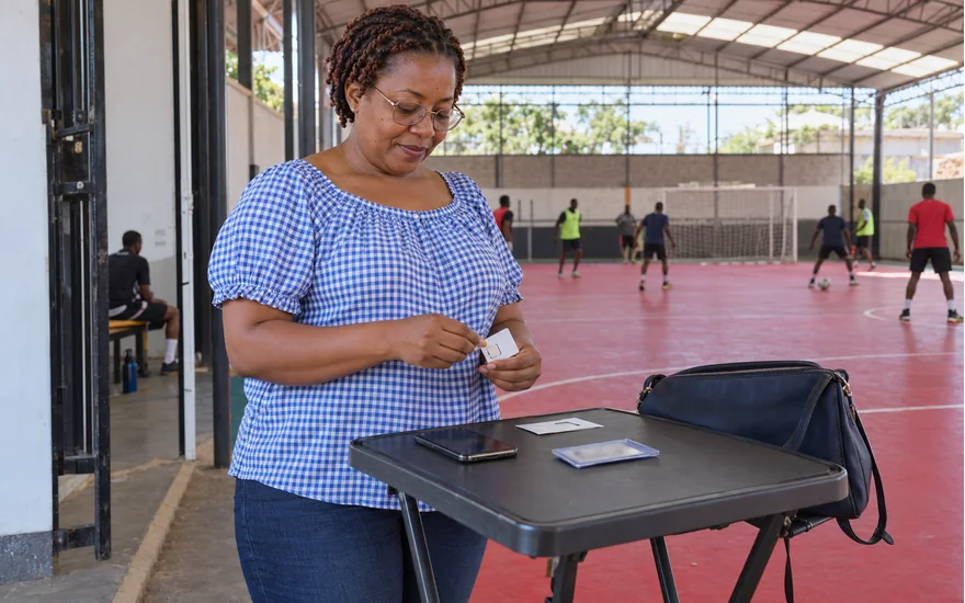 Mwanamke akiandaa SIM na simu karibu na mlango wa ukumbi wa futsal Tanzania